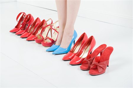 Line of red shoes with a woman standing in blue shoes Stock Photo - Premium Royalty-Free, Code: 693-06021451