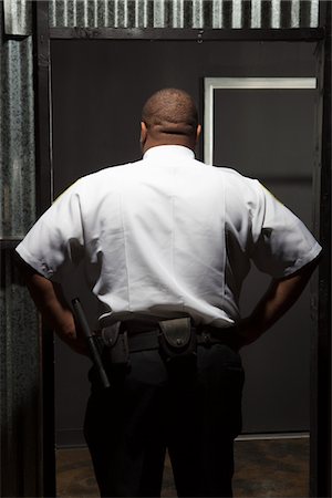 Security guard stands with hands on hips rear view Stock Photo - Premium Royalty-Free, Code: 693-06022147