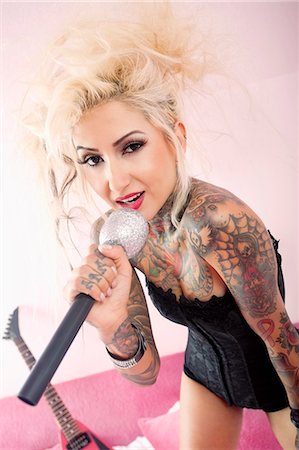 simsearch:693-06120700,k - Portrait of a tattooed blond woman singing with microphone Stock Photo - Premium Royalty-Free, Code: 693-06120713