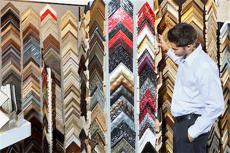 Side view of a young man browsing at a frame store with hands in pockets Stock Photo - Premium Royalty-Free, Code: 693-06121023