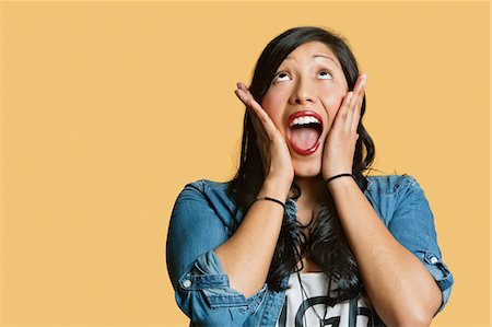 simsearch:693-06324124,k - Surprised young woman with head in hands looking up over colored background Stock Photo - Premium Royalty-Free, Code: 693-06121359
