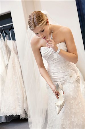 simsearch:693-06325147,k - Beautiful confused woman in wedding dress holding footwear while looking down Stock Photo - Premium Royalty-Free, Code: 693-06324070