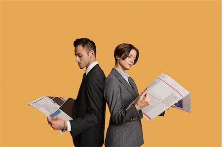 short hair - Business partners standing back to back while reading newspaper Stock Photo - Premium Royalty-Free, Code: 693-06324098