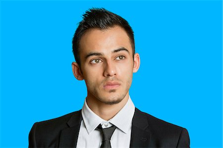 Thoughtful young businessman looking away over colored background Stock Photo - Premium Royalty-Free, Code: 693-06324100