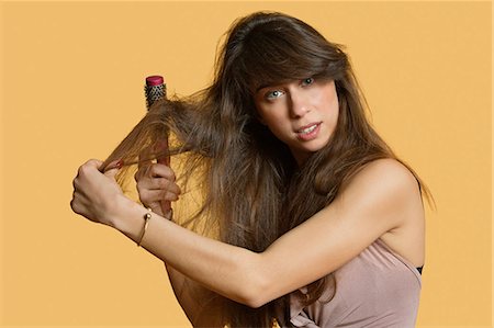 simsearch:693-06323962,k - Portrait of a young woman brushing hair over colored background Stock Photo - Premium Royalty-Free, Code: 693-06324116
