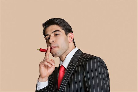 simsearch:693-06324124,k - Portrait of a young businessman with red chili pepper imitating as smoking cigarette Stock Photo - Premium Royalty-Free, Code: 693-06324148