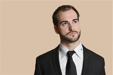 Young businessman looking away over colored background Stock Photo - Premium Royalty-Free, Code: 693-06324182
