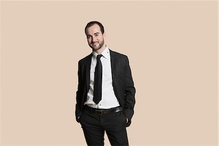 Portrait of a young businessman with hands in pockets over colored background Stock Photo - Premium Royalty-Free, Code: 693-06324183