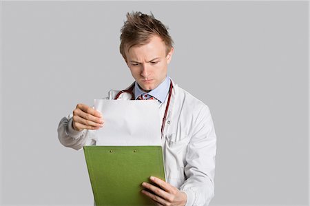 report (written account) - Male doctor reading medical records over gray background Stock Photo - Premium Royalty-Free, Code: 693-06324210