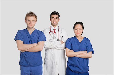 simsearch:693-06324311,k - Portrait of diverse healthcare workers standing with hands folded over gray background Stock Photo - Premium Royalty-Free, Code: 693-06324239