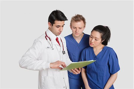 simsearch:693-06324311,k - Three healthcare professional discussing medical report over gray background Stock Photo - Premium Royalty-Free, Code: 693-06324233