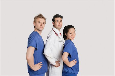simsearch:693-06324311,k - Portrait of medical team standing hands on hips over gray background Stock Photo - Premium Royalty-Free, Code: 693-06324242