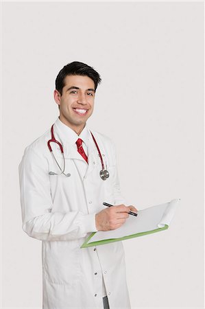 report (written account) - Portrait of a cheerful Indian male doctor holding a medical chart over light gray background Stock Photo - Premium Royalty-Free, Code: 693-06324252