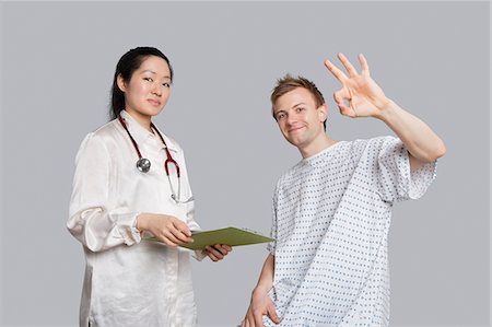 simsearch:693-06324311,k - Portrait of patient gesturing okay with doctor holding a clipboard Stock Photo - Premium Royalty-Free, Code: 693-06324294