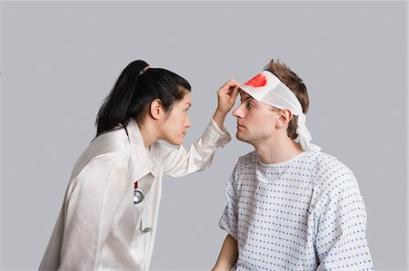 simsearch:693-06324311,k - Young female doctor examining an injured male patient Stock Photo - Premium Royalty-Free, Code: 693-06324299