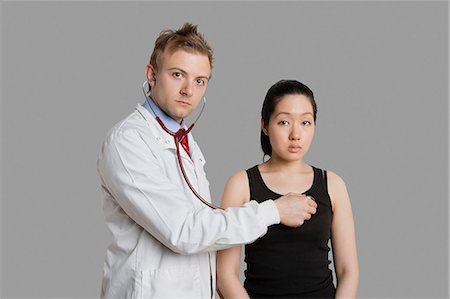 simsearch:693-06324311,k - Doctor examining female patient with stethoscope Stock Photo - Premium Royalty-Free, Code: 693-06324303