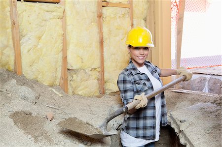 shovel (hand tool for digging) - Portrait of a happy female contractor digging sand at construction site Stock Photo - Premium Royalty-Free, Code: 693-06324479