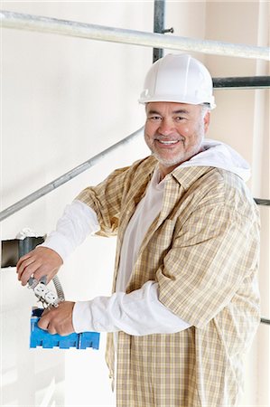 Portrait of a cheerful mature man holding construction equipment Stock Photo - Premium Royalty-Free, Code: 693-06324492