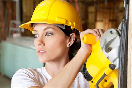 Female construction worker cutting wood with a power saw while looking away Stock Photo - Premium Royalty-Free, Code: 693-06324509