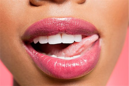 Cropped image of woman licking pink lipstick Stock Photo - Premium Royalty-Free, Code: 693-06324639