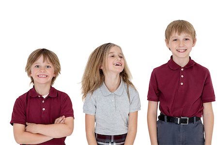 portrait of boy with arms crossed - Portrait of cheerful school children in uniform over white background Stock Photo - Premium Royalty-Free, Code: 693-06324785