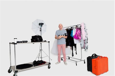 photographer (male) - Portrait of senior photographer standing in front of clothes rack in studio Stock Photo - Premium Royalty-Free, Code: 693-06324872