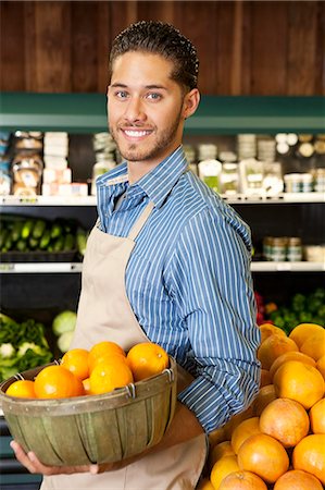 fruits stores - Happy salesperson with basket full of oranges in market Stock Photo - Premium Royalty-Free, Code: 693-06324937