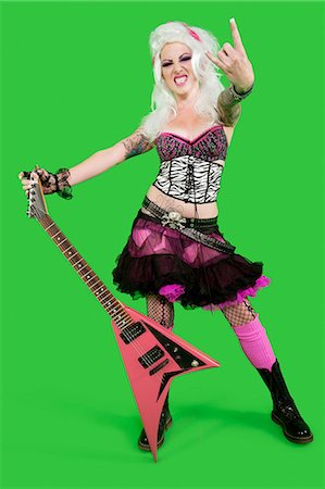 punk rocker (female) - Portrait of young punk woman holding guitar with rock & roll hand sign over green background Stock Photo - Premium Royalty-Free, Code: 693-06324968