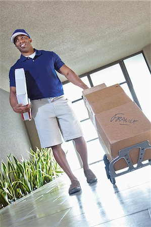 package - Happy African American delivery man Stock Photo - Premium Royalty-Free, Code: 693-06323977