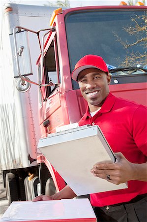 package - Portrait of a happy African American man holding clipboard with delivery truck in background Stock Photo - Premium Royalty-Free, Code: 693-06323989