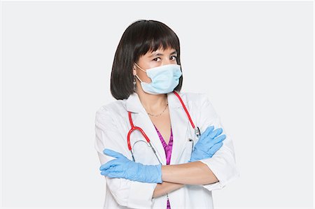 surgical mask - Portrait of female veterinarian standing arms crossed over gray background Stock Photo - Premium Royalty-Free, Code: 693-06378726