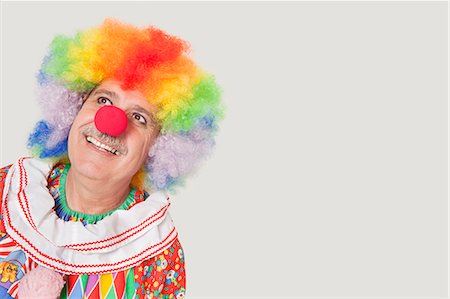 Happy senior clown looking up against gray background Stock Photo - Premium Royalty-Free, Code: 693-06378843