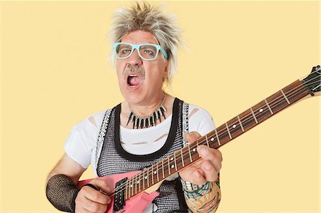 Senior male punk musician playing guitar over yellow background Stock Photo - Premium Royalty-Free, Code: 693-06378851