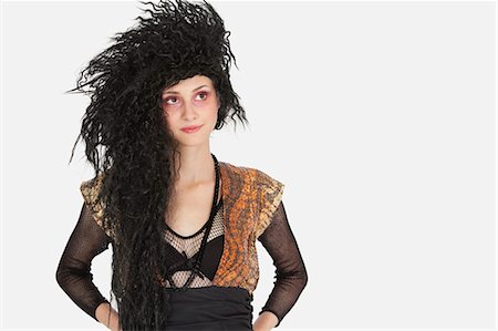 simsearch:693-06435933,k - Beautiful young Goth woman with teased hair looking away over gray background Stock Photo - Premium Royalty-Free, Code: 693-06378887