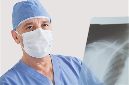 radiographs - Portrait of senior male surgeon examining x-ray over gray background Stock Photo - Premium Royalty-Free, Code: 693-06378911