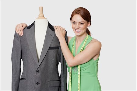 Portrait of beautiful female dressmaker standing with tailor's dummy over gray background Stock Photo - Premium Royalty-Free, Code: 693-06378979