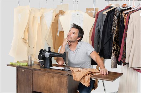 Mature male tailor thinking while sitting at sewing machine with fabric Stock Photo - Premium Royalty-Free, Code: 693-06378987
