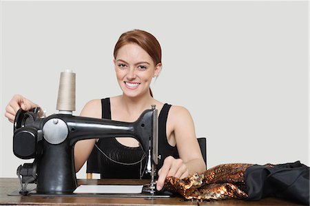 Portrait of young female tailor stitching cloth on sewing machine over colored background Stock Photo - Premium Royalty-Free, Code: 693-06379020