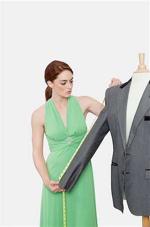 fashion designer - Female tailor measuring sleeve of suit over gray background Stock Photo - Premium Royalty-Free, Code: 693-06379032