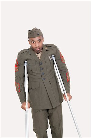 Portrait of African American military officer with crutches, studio shot on gray background Stock Photo - Premium Royalty-Free, Code: 693-06379084