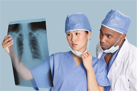 Two surgeons examining x-ray report over light blue background Stock Photo - Premium Royalty-Free, Code: 693-06379081