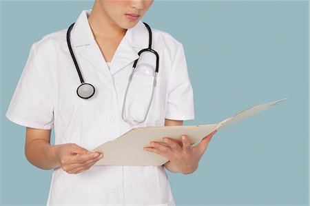 reporting - Midsection of a female doctor reading medical report over light blue background Stock Photo - Premium Royalty-Free, Code: 693-06379178