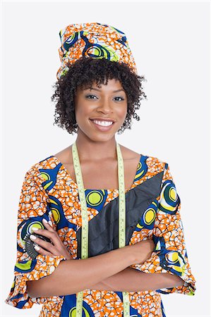 Portrait of young female fashion designer in African print attire standing hands folded over gray background Stock Photo - Premium Royalty-Free, Code: 693-06379248