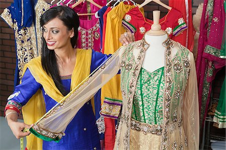 Indian female dressmaker measuring traditional outfit at design studio Stock Photo - Premium Royalty-Free, Code: 693-06379303