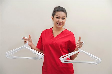 female native american clothing - Portrait of female housekeeper holding white plastic hangers against gray background Stock Photo - Premium Royalty-Free, Code: 693-06379355