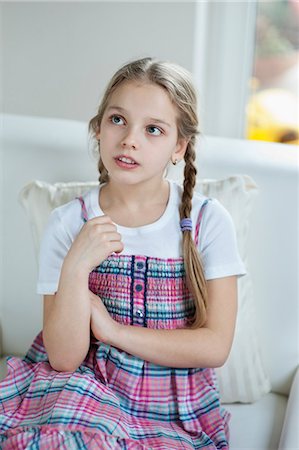 preteen girl - Young girl thinking while sitting on sofa Stock Photo - Premium Royalty-Free, Code: 693-06379384