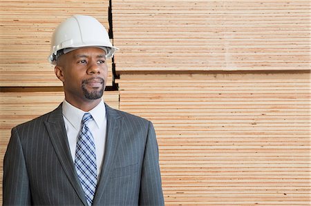 simsearch:693-06379747,k - Confident African American male contractor looking away while standing in front of stacked wooden planks Stock Photo - Premium Royalty-Free, Code: 693-06379696