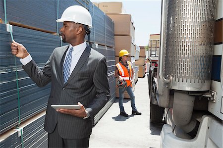 simsearch:693-06379747,k - African American male engineer inspecting planks while female worker standing by flatbed truck Stock Photo - Premium Royalty-Free, Code: 693-06379717