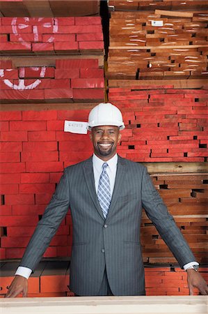simsearch:693-06379747,k - Portrait of happy African American male contractor with stacked wooden planks in background Stock Photo - Premium Royalty-Free, Code: 693-06379739