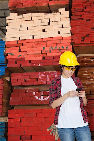 simsearch:693-06379747,k - Asian female industrial worker using cell phone with stacked wooden planks in background Stock Photo - Premium Royalty-Free, Code: 693-06379731